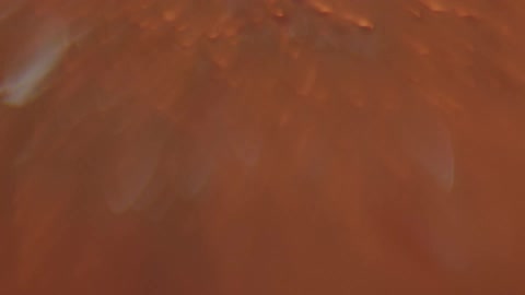 Light brightens on orange colored bubbling flowing liquid