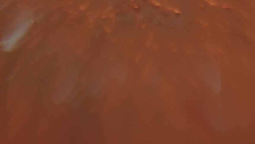 Light brightens on orange colored bubbling flowing liquid