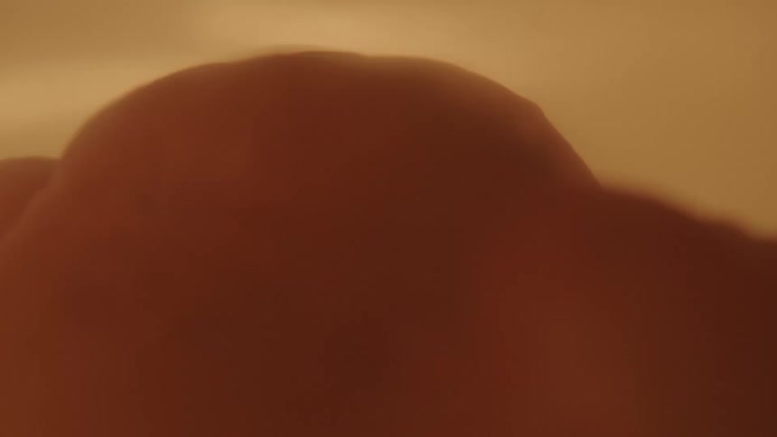 A baby twists and floats with hues of light yellow and then darkness