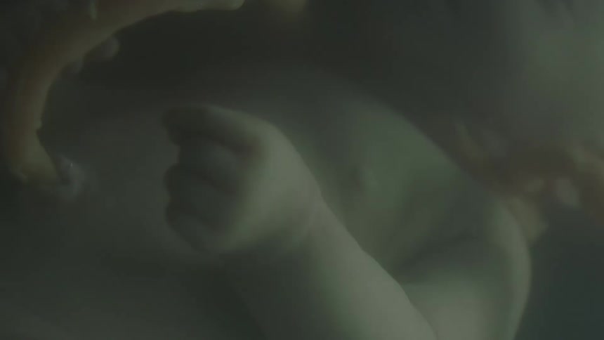 Bubble floats upward as unborn baby and umbilical cord float in fluid