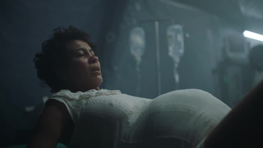 A pregnant woman is leaning back on a bed in a hospital about to give birth