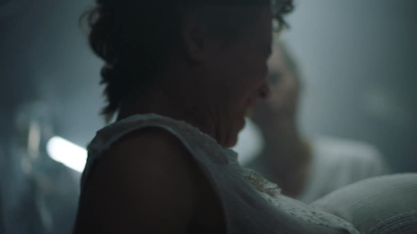 A woman is in labor on a bed in a hospital setting with medical staff around her