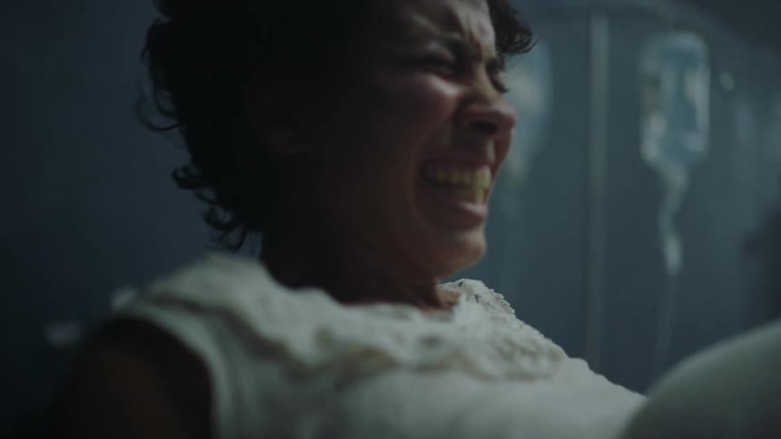 Mother sits up in bed grimacing through labor