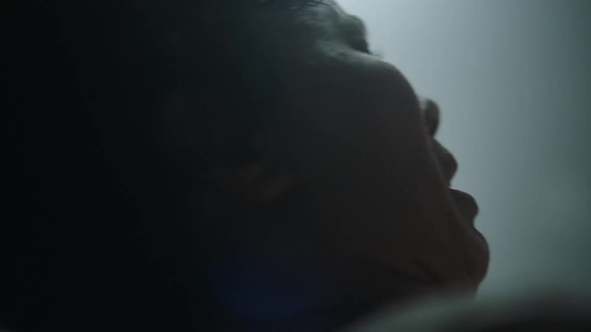 Woman in labor pains delivers a baby in a dimly lit room at a hospital