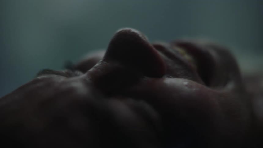 Close up of a womans face in pain during childbirth in a dimly lit hospital room