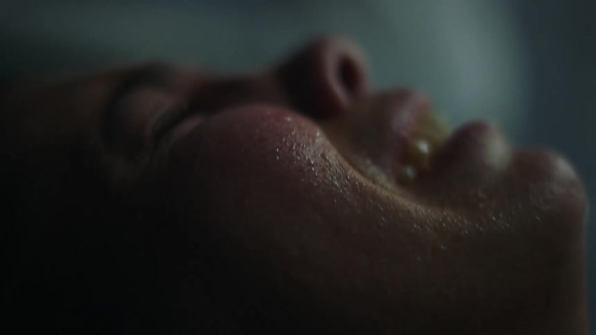 Close up of a womans face in pain giving birth in a dimly lit hospital room