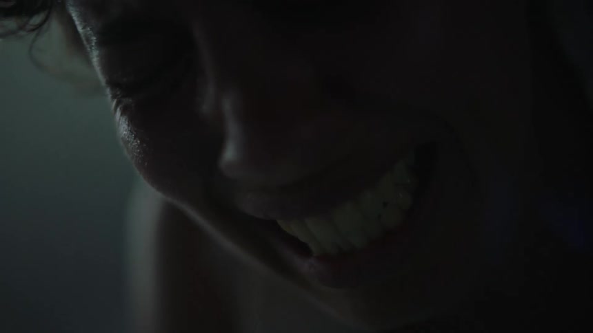 A close view of the face of a woman bent over in pain and crying while indoors
