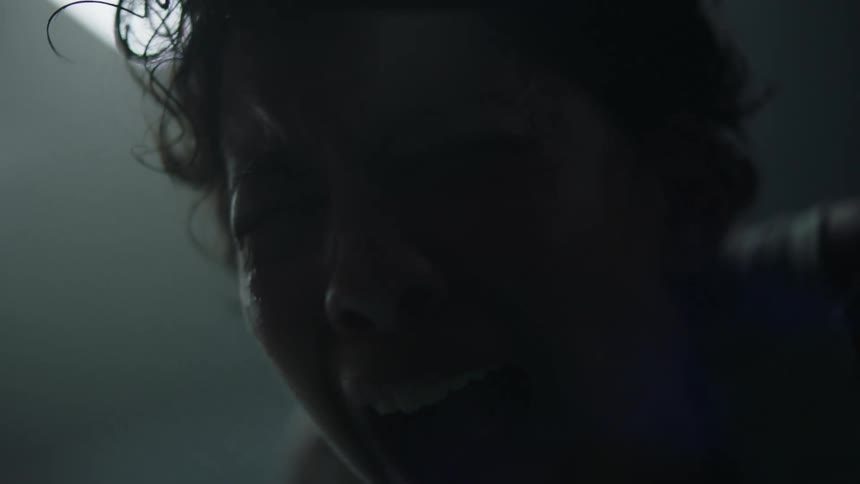A woman is standing and panting then screams in pain while indoors
