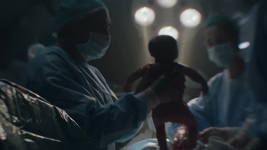 A doctor delivering a newborn during a c section birth