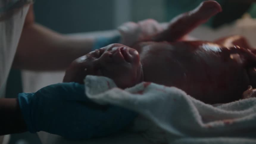 Doctors and nurses rubbing the blood on the skin of a newborn baby with towels in a hospital