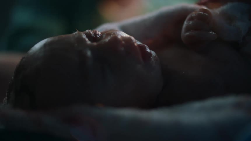 Medical personnel in scrubs carefully handle newborn baby in delivery room