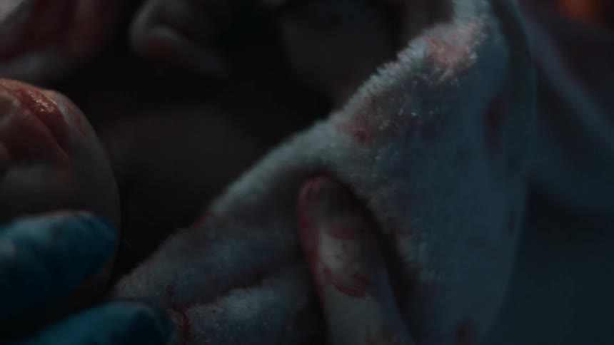 A newborn baby is swaddled by medical staff right after birth