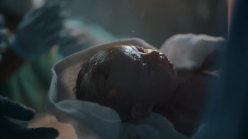 Medical personnel in delivery room handle newborn baby