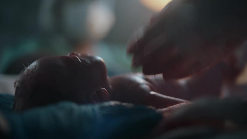 Medical workers in an operating room clean and wrap a newborn baby in a towel