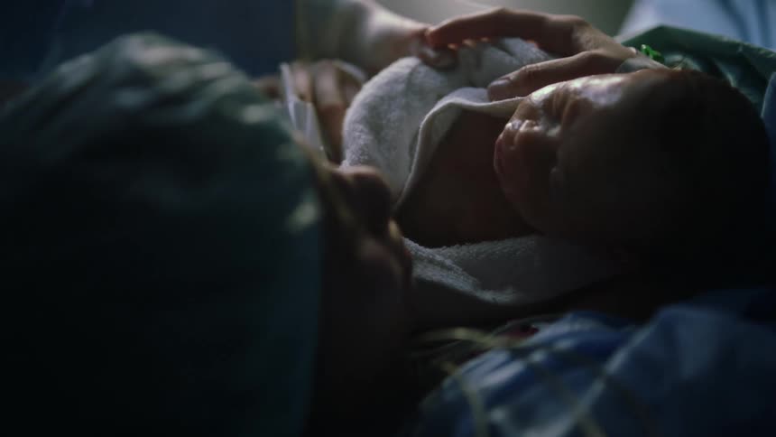 A mother holding a newborn after giving birth in a hospital