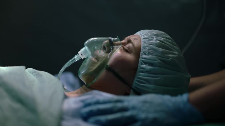 A female patient with an oxygen mask on a hospital bed