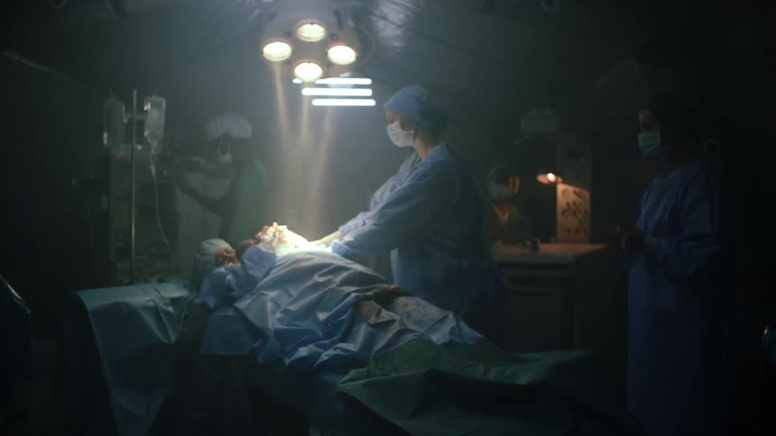 Mother holding newborn baby on the bed in a dimly lit hospital room