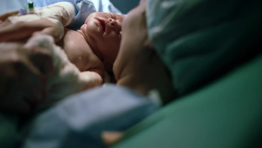 Nurse placing newborn on the mother after delivery