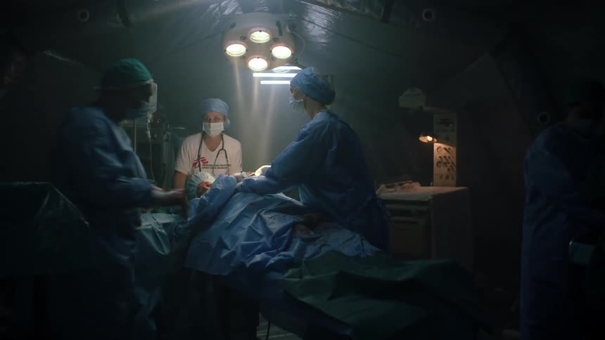 A woman is lying on a surgical stretched in the operating room as medical staff prepares for the procedure