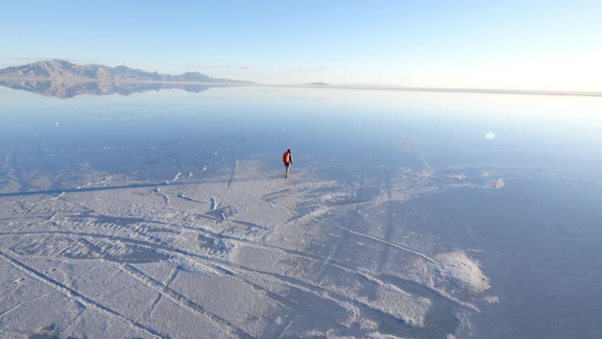 A person is hiking over a frozen over body of water