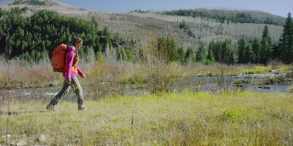 A young woman backpacking along a river