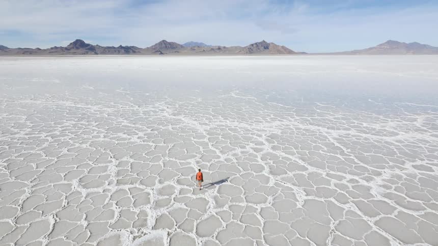 A man is walking across a salt flat
