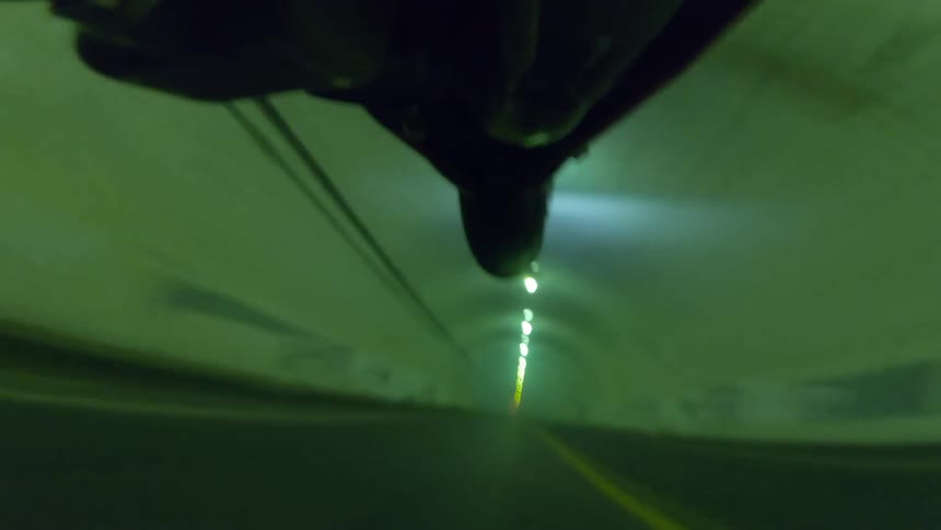 A motorcycle driving through a tunnel lifts the front wheel off the road