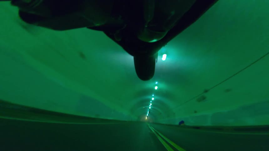 A motorcycle driving through a tunnel with one wheel lifted off the ground