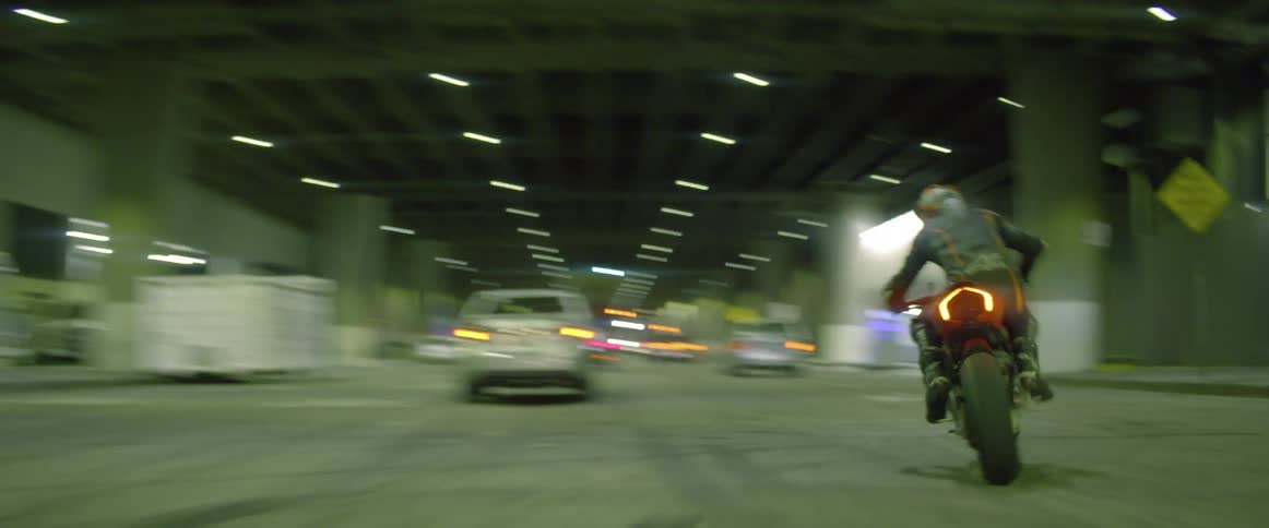 A person driving a motorcycle through a tunnel weaves in and out of traffic