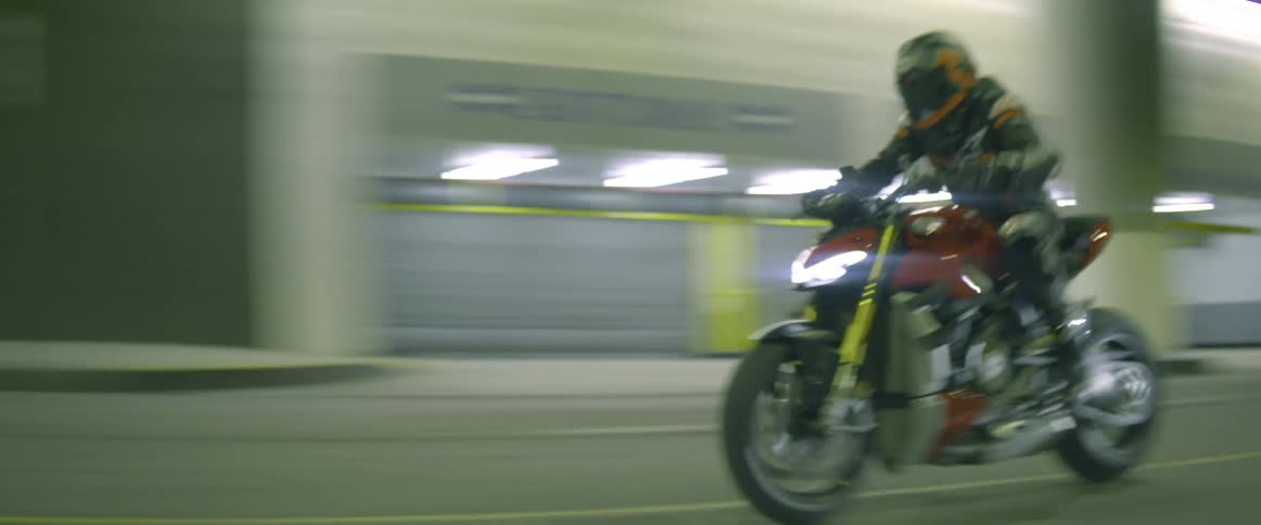 A person driving a motorcycle weaves in and out of traffic