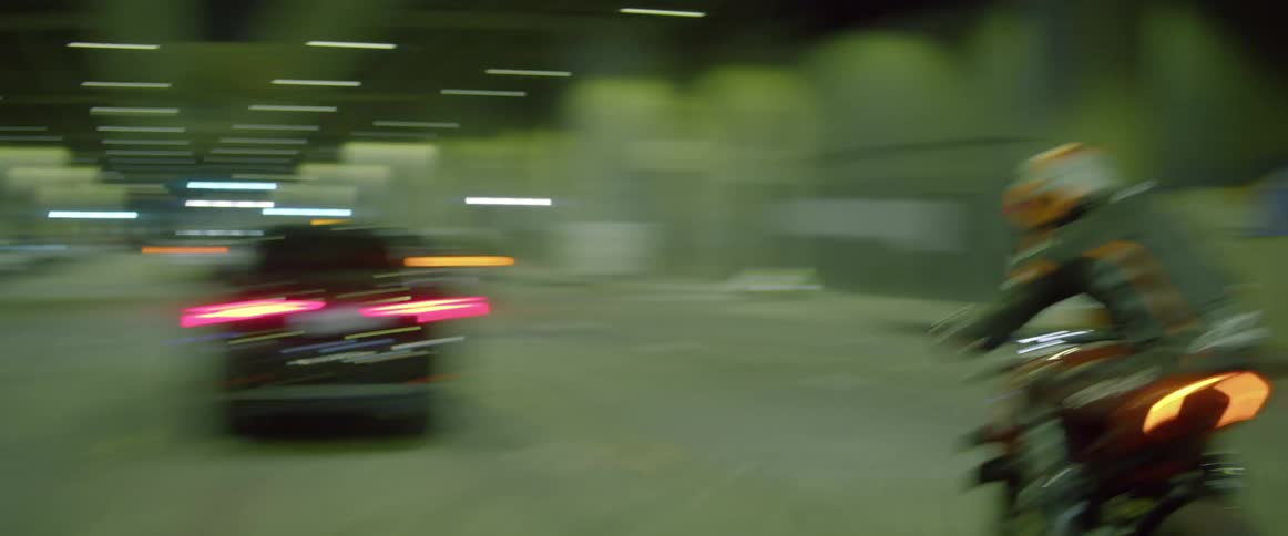 A motorcyclist speeds and weaves through vehicles driving through a tunnel