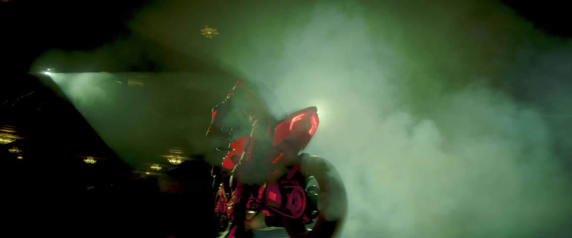 Red futuristic motorcycle burning rubber while parked on stage