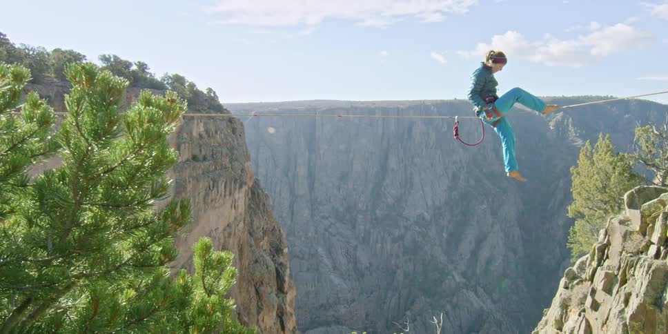 Someone sitting on a tightrope that spans a canyon
