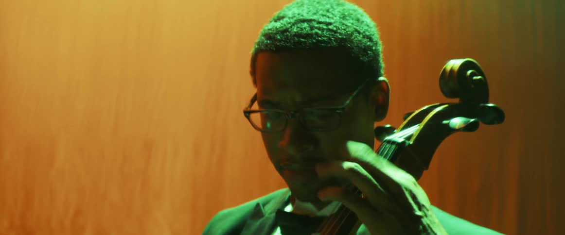 Young musician happily plays the violoncello on stage