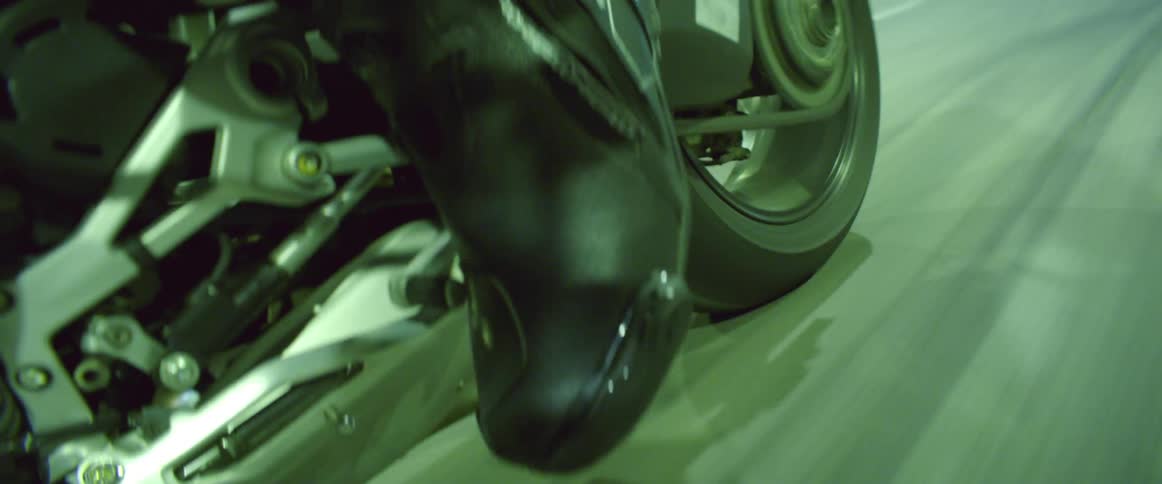 A man keeps his foot on the pedal as he speeds down a road on his motorcycle at night