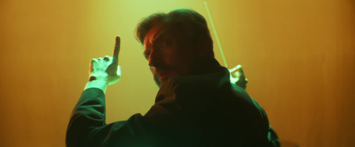 A musical conductor has his arms raised ready for the music when he turns to look behind him