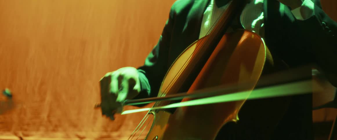 Man sitting down in front of a music stand playing the cello