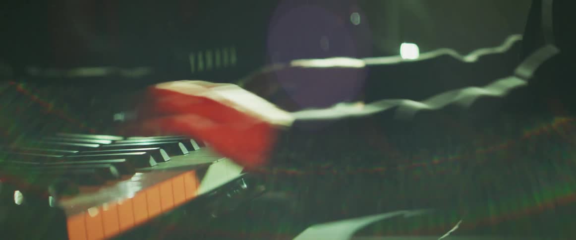 Pianist wearing a tuxedo playing a grand piano on stage in a concert
