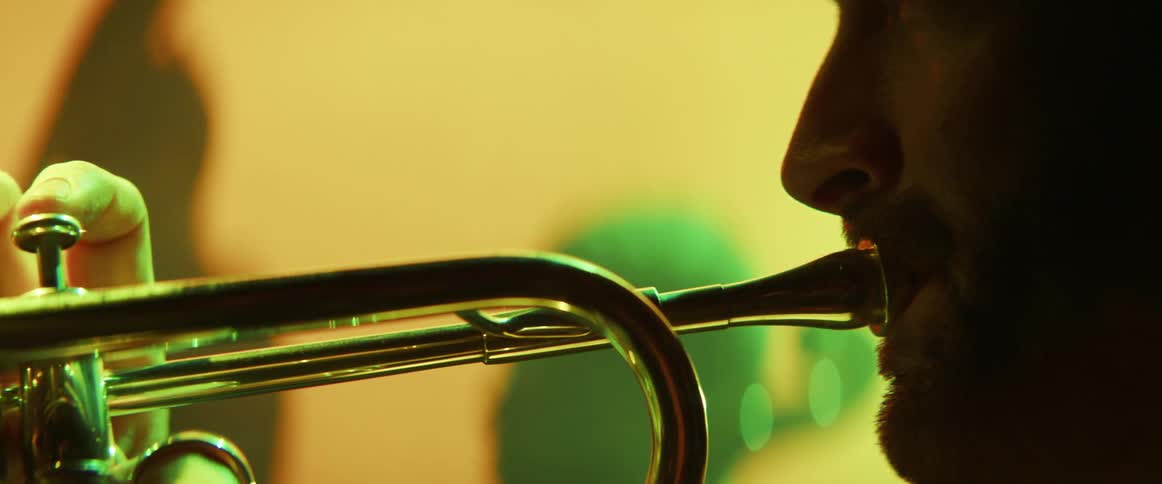 A bearded man playing a trumpet