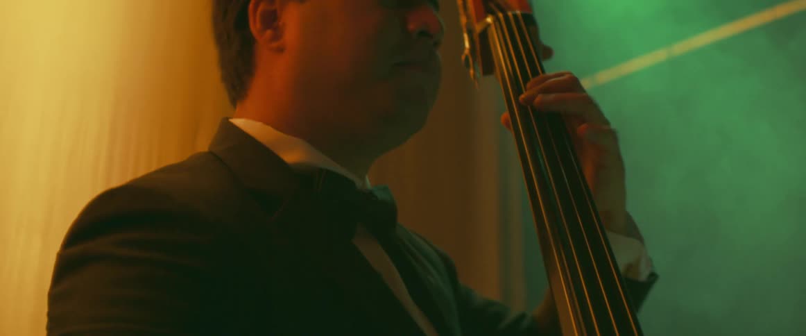 A man plays a stringed musical instrument while moving his head to the music