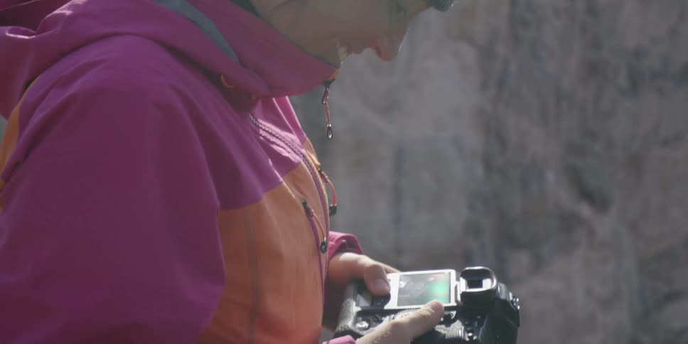 Woman wearing a knitted cap looking down at her camera