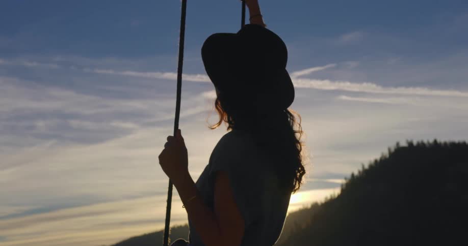 A woman swinging on an outdoor swing by a forest