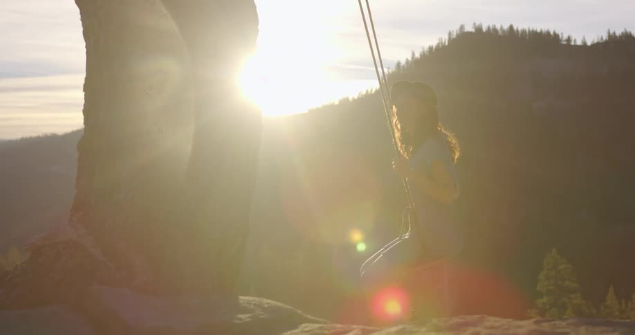 A young woman swings on a swing in a forest area