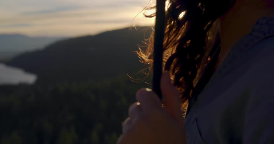 A woman is outdoors while the sun is setting in the horizon