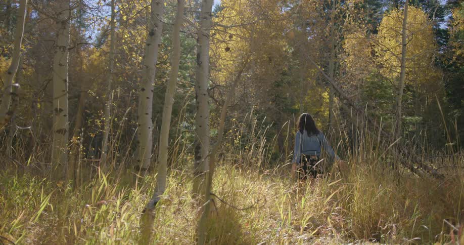 Girl walks into forest wearing denim jacket and skirt