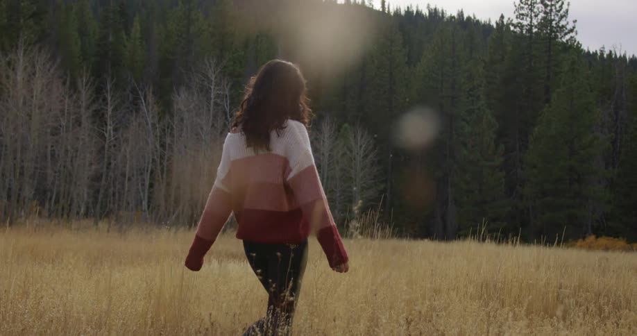 A woman is walking outdoors in a field of grass