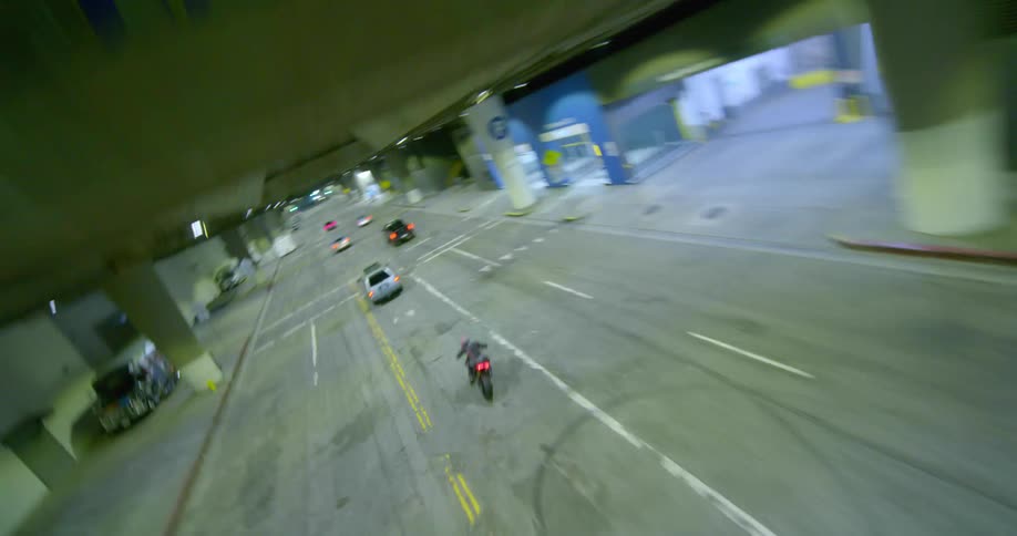 Aerial drone shot of a motorcycle driving at full speed on the city streets at night