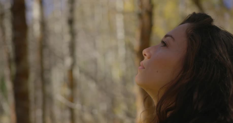 A woman takes pictures and looks around the forest