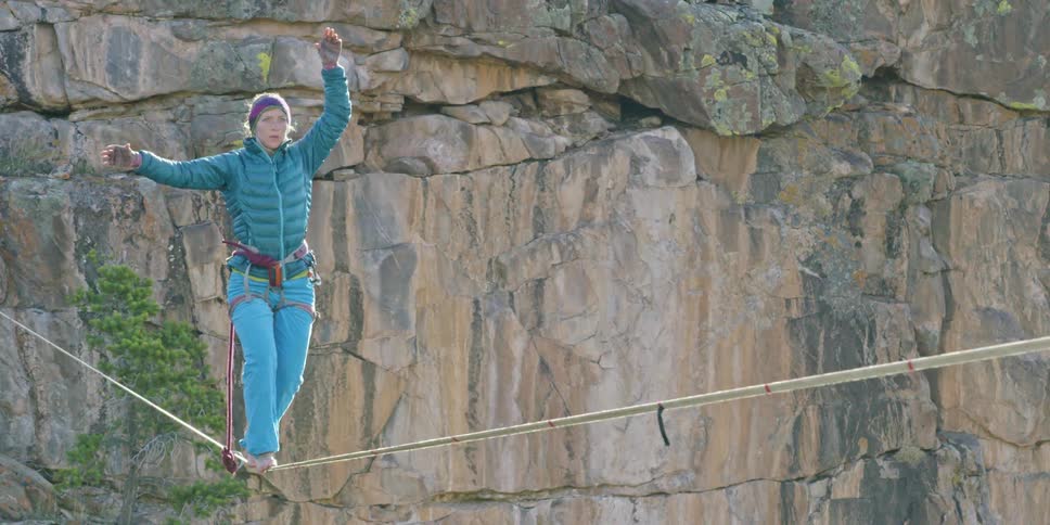 Woman balancing and walking on a tightrope over a canyon