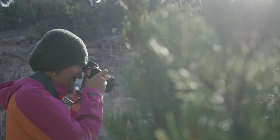 Woman smiling and taking pictures through trees